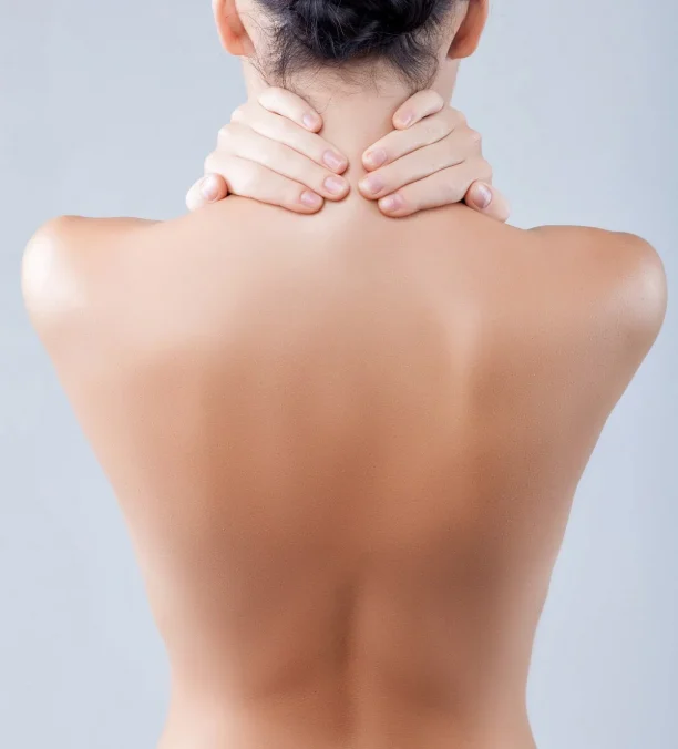 Woman with smooth bare back massaging neck after spa treatment.