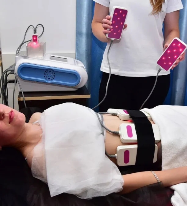 Laser lipo body slimming pads placed on woman's abdomen in clinic.